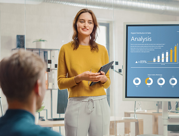 Woman presenting a screen in front of a room with analyytic data